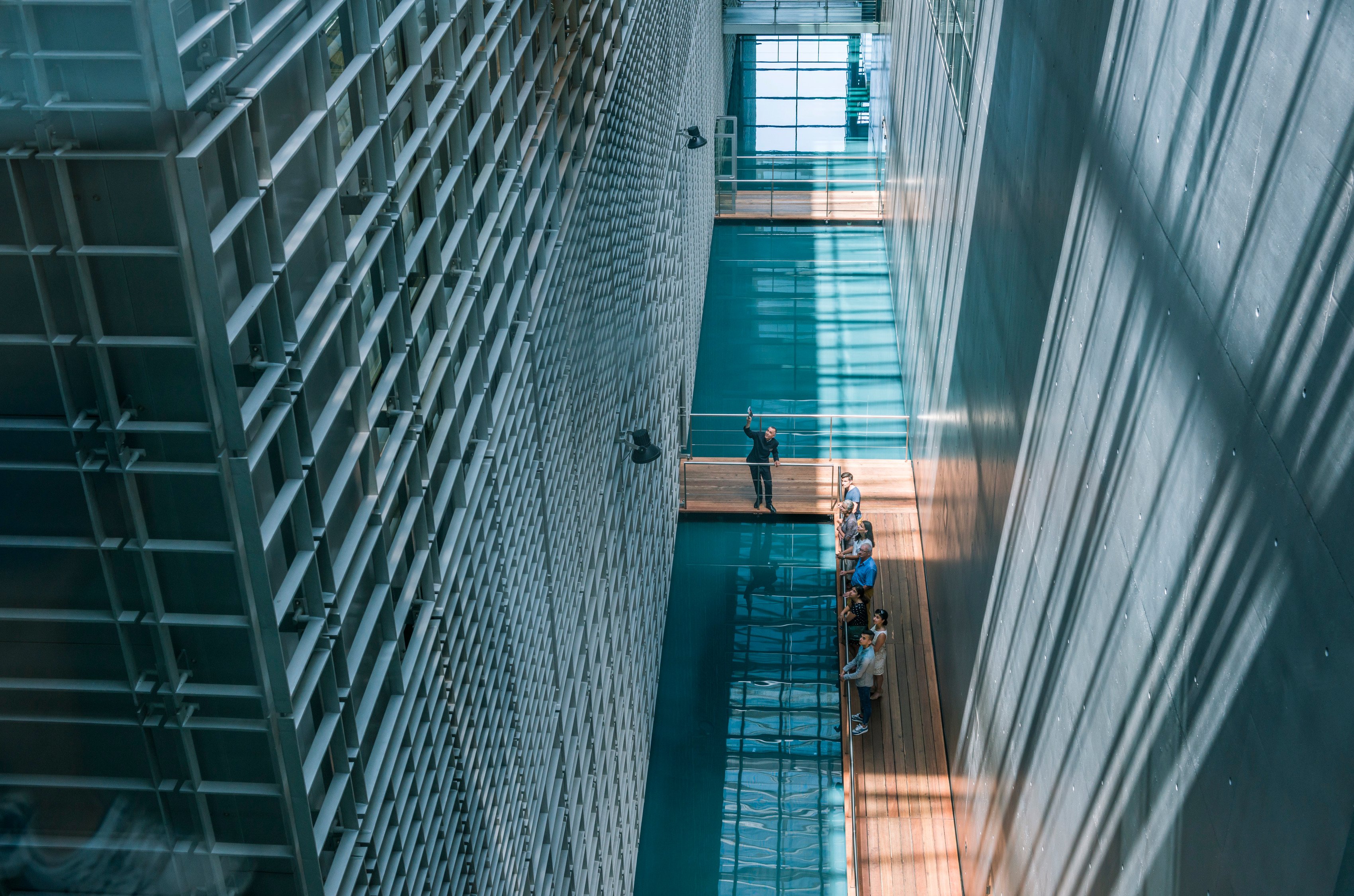 People on a footbridge between two building wings separated by a water canal.