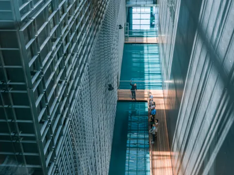 People on a footbridge between two building wings separated by a water canal.