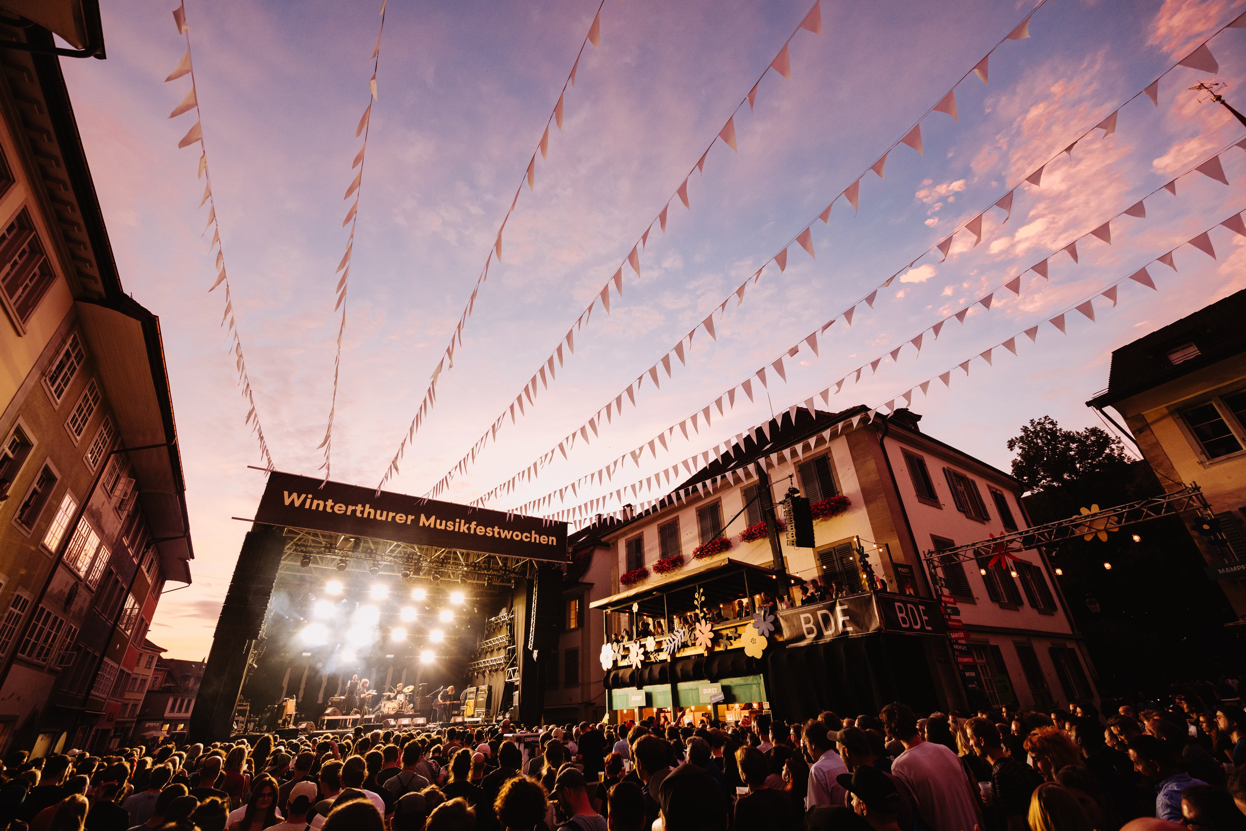 Ambiance nocturne, foule devant la scène de concert en arrière-plan.