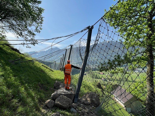 Le collaborateur se tient sur une grosse pierre qui est tombée dans une clôture.