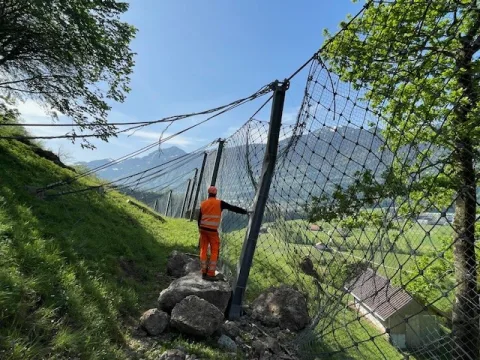 Le collaborateur se tient sur une grosse pierre qui est tombée dans une clôture.