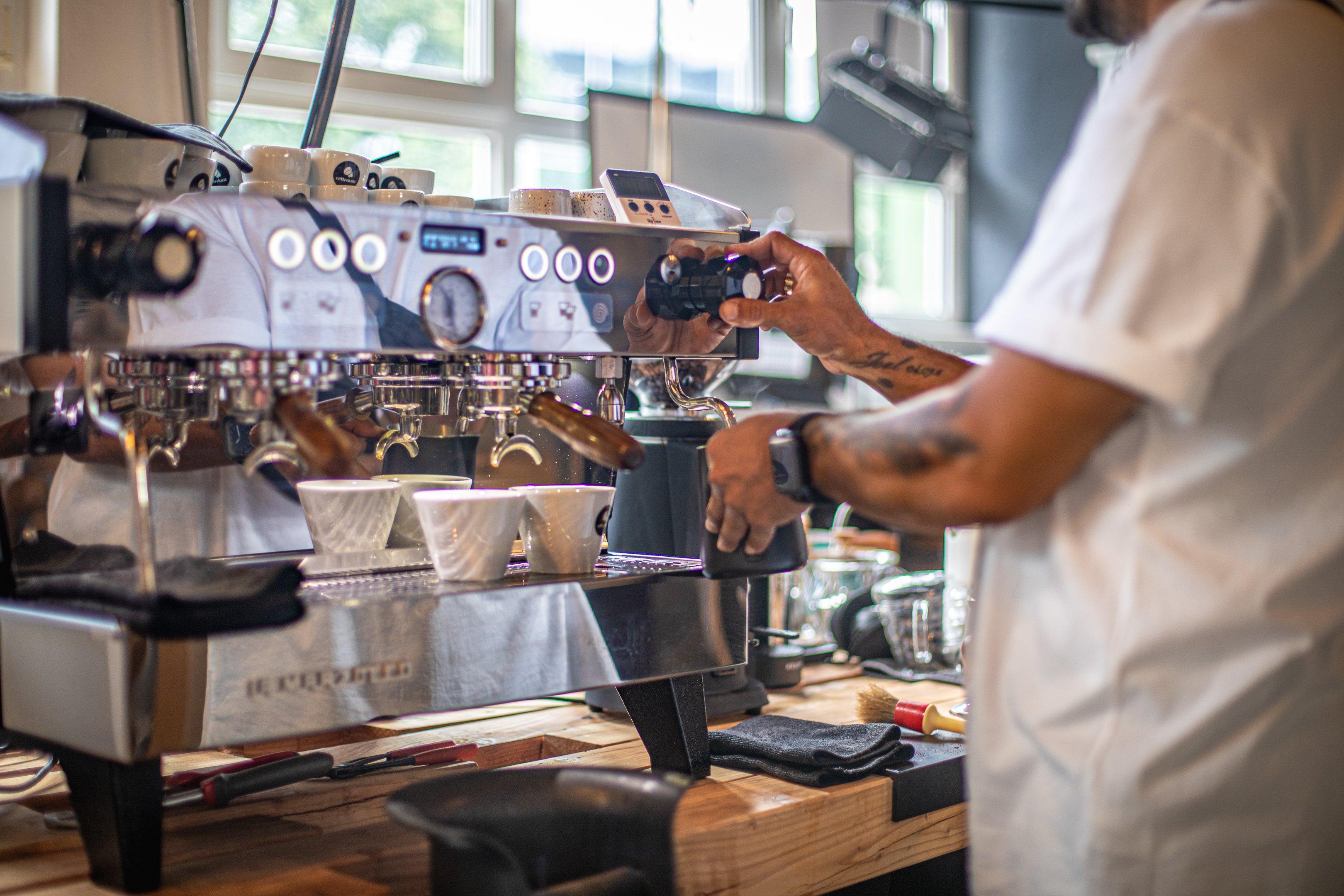 Inhaber Cem steht an der Kaffeemaschine und macht Milchschaum.