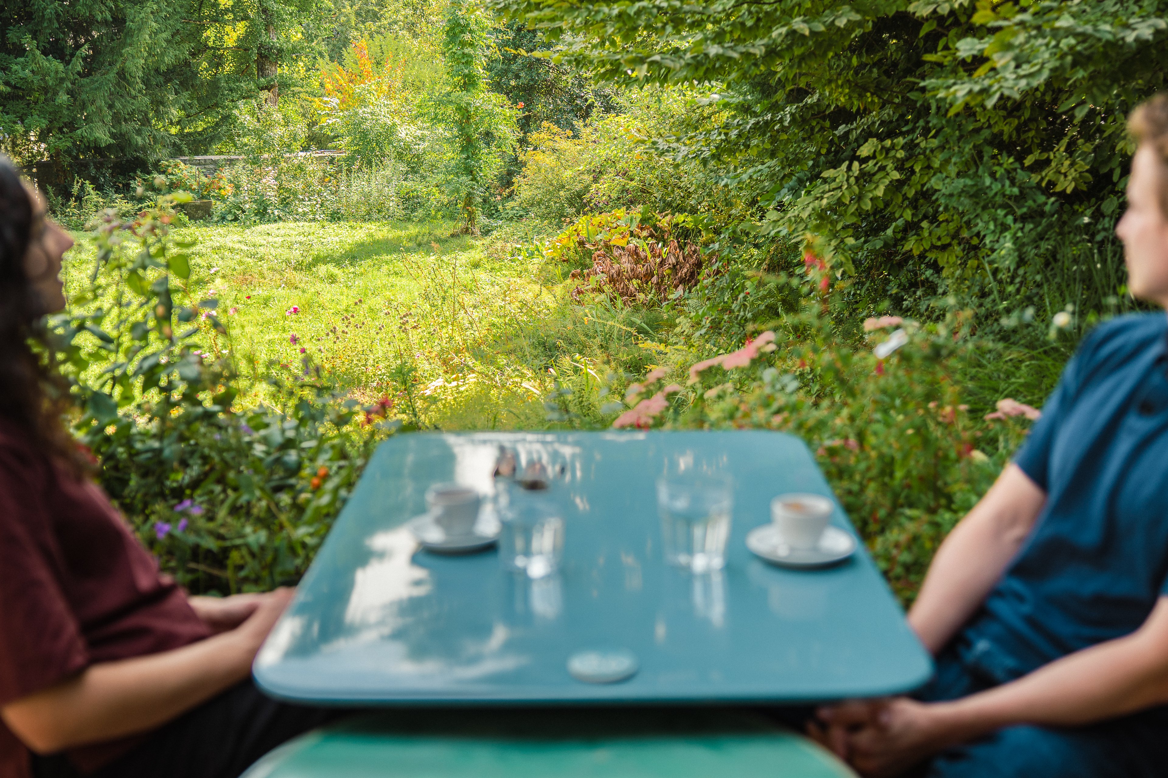 Due persone sono sedute a un tavolo con vista su un rigoglioso giardino.