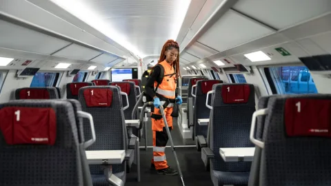 Mitarbeiterin reinigt Oberdeck eines Zuges mit Staubsauger.