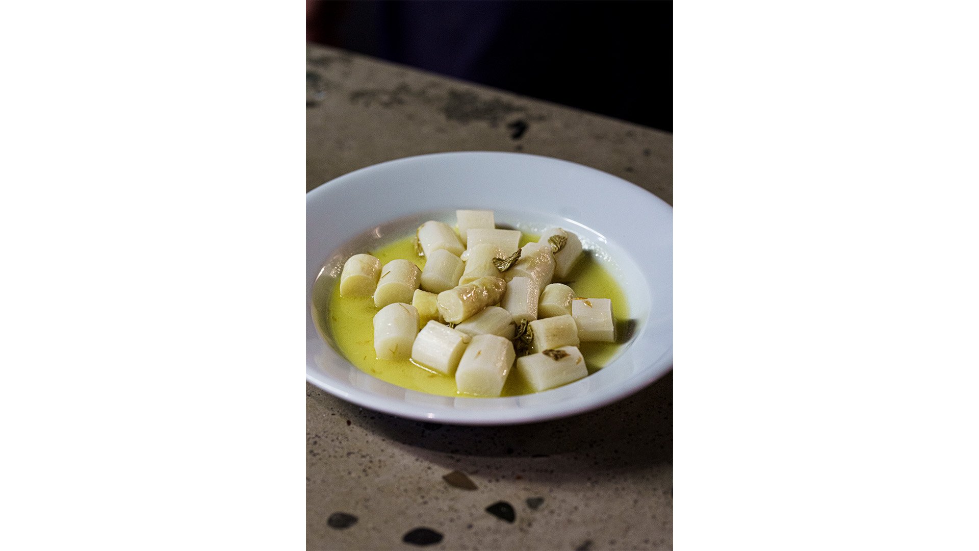 Un piatto bianco con sopra del cibo (asparagi bianchi con olio d’oliva) del locale Heisswein.