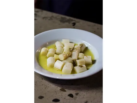 Un piatto bianco con sopra del cibo (asparagi bianchi con olio d’oliva) del locale Heisswein.