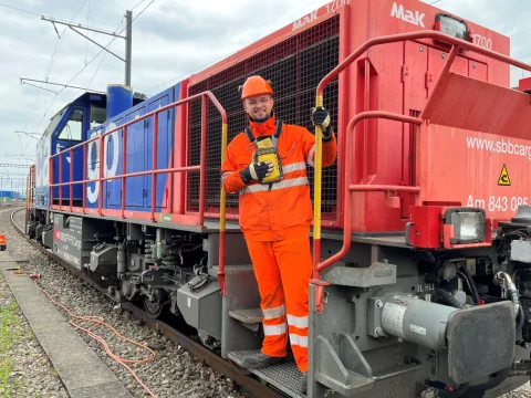 Rangierspezialisten Sabit Medi steht auf dem Trittbrett der Rangierlok Am 843 und hält sich an der Haltestange fest.