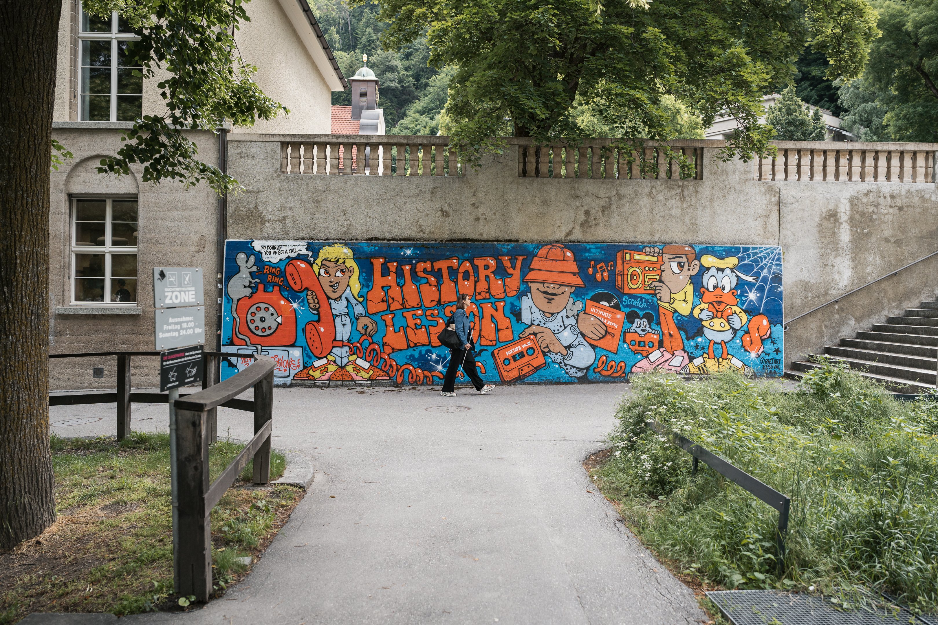 Una donna passa davanti a un muro con graffiti colorati.