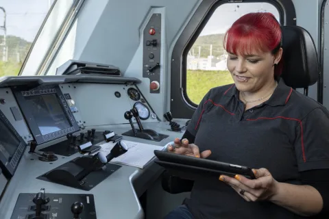 Lokführerin im Führerstand am Tablet