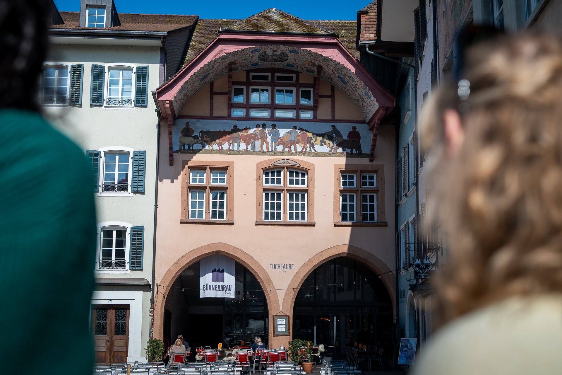 Zwei Frauen blicken an die bemalte Fassade der Tuchlaube Café Bar.