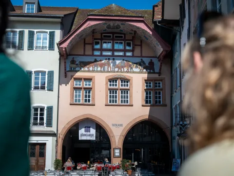 Zwei Frauen blicken an die bemalte Fassade der Tuchlaube Café Bar.