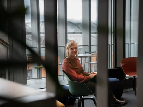 Sandra Schwander sitzzt auf einem grünen Stuhl und schaut in die Kamera. Sie hat einen roten Pullover an.