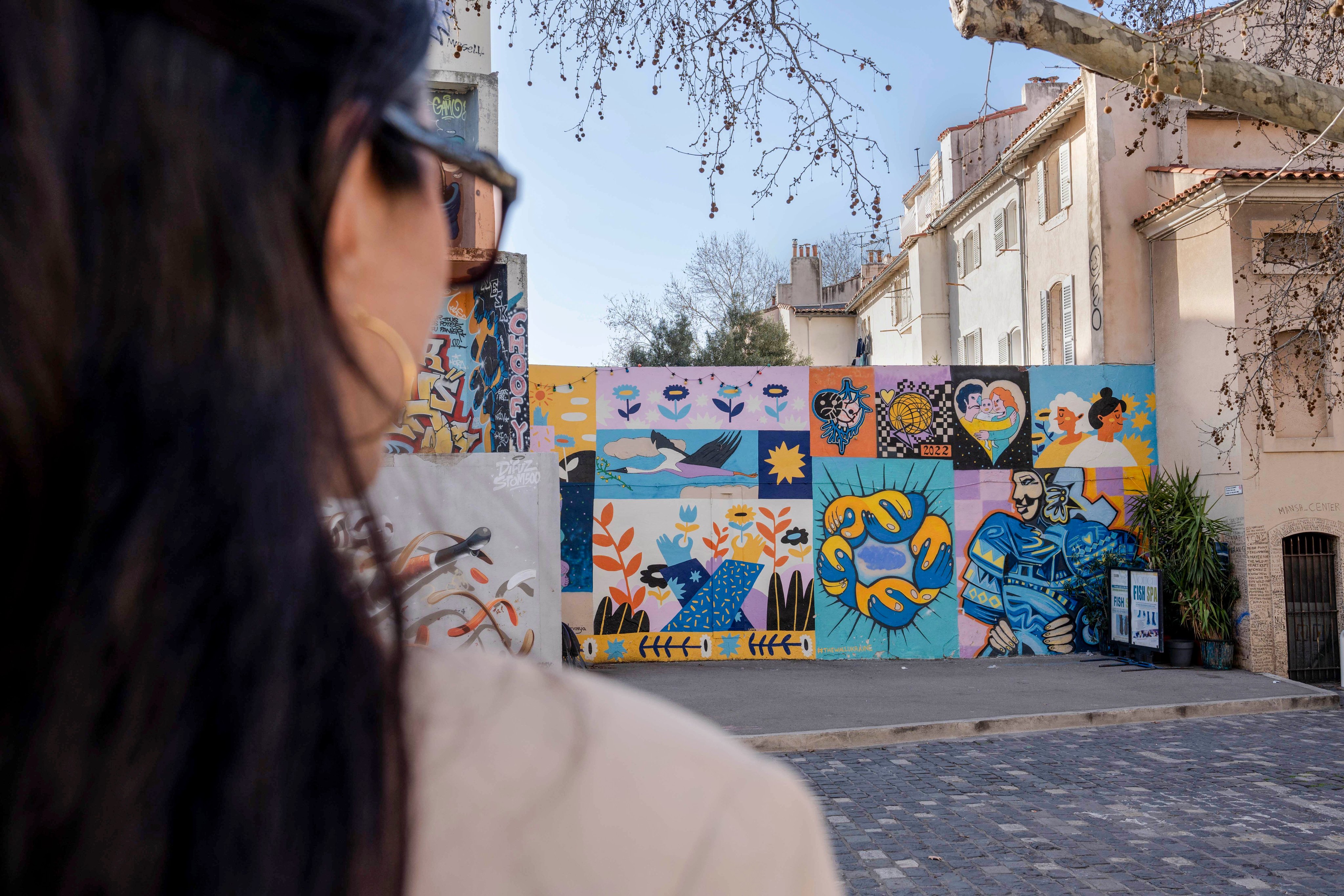 Personne observant une fresque murale dans le quartier du Panier, témoignant de la scène artistique active et de la mise en valeur de la créativité à Marseille.