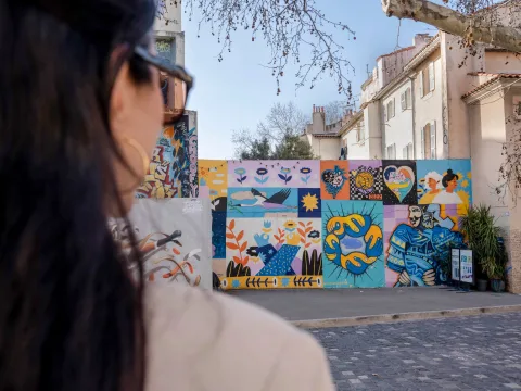 Personne observant une fresque murale dans le quartier du Panier, témoignant de la scène artistique active et de la mise en valeur de la créativité à Marseille.