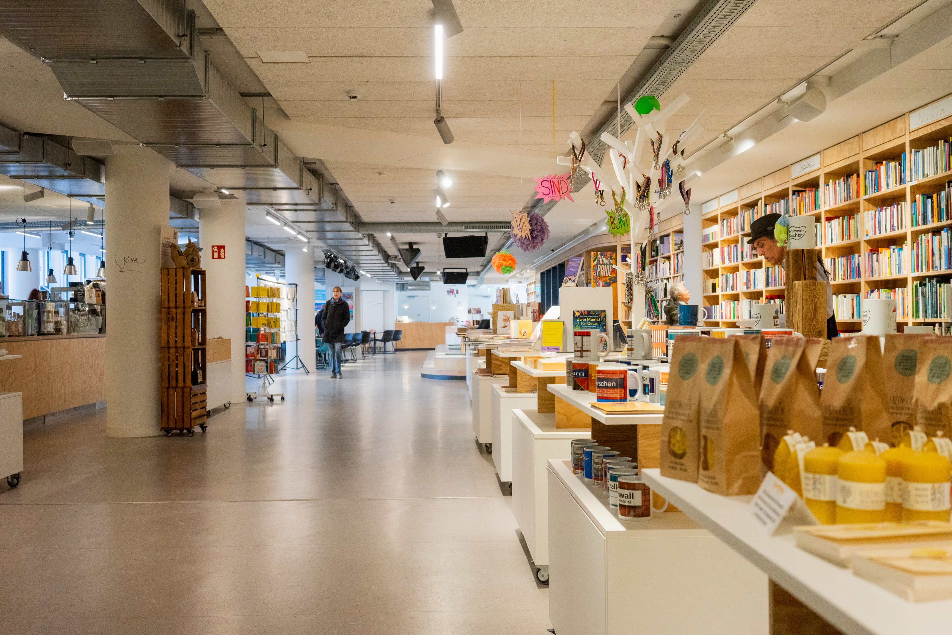 Ein tiefer, heller Raum mit Bücherregalen und Regalen mit unterschiedlichen Produkten.