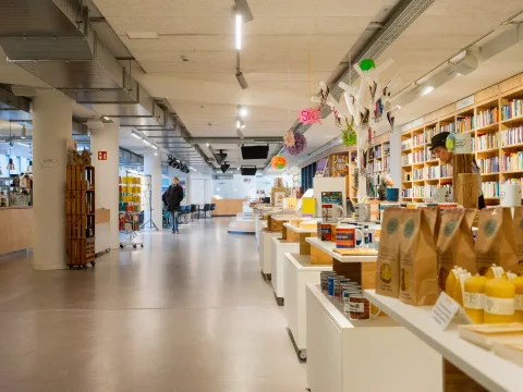 Ein tiefer, heller Raum mit Bücherregalen und Regalen mit unterschiedlichen Produkten.