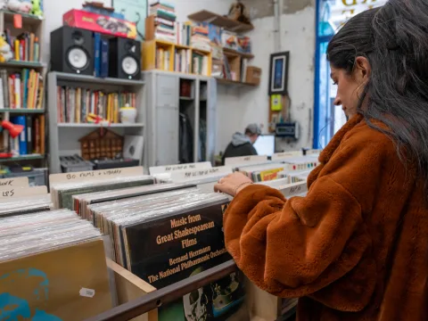 Une personne fouillant méthodiquement la collection de disques en vinyle dans une petite boutique remplie de livres et de musique.