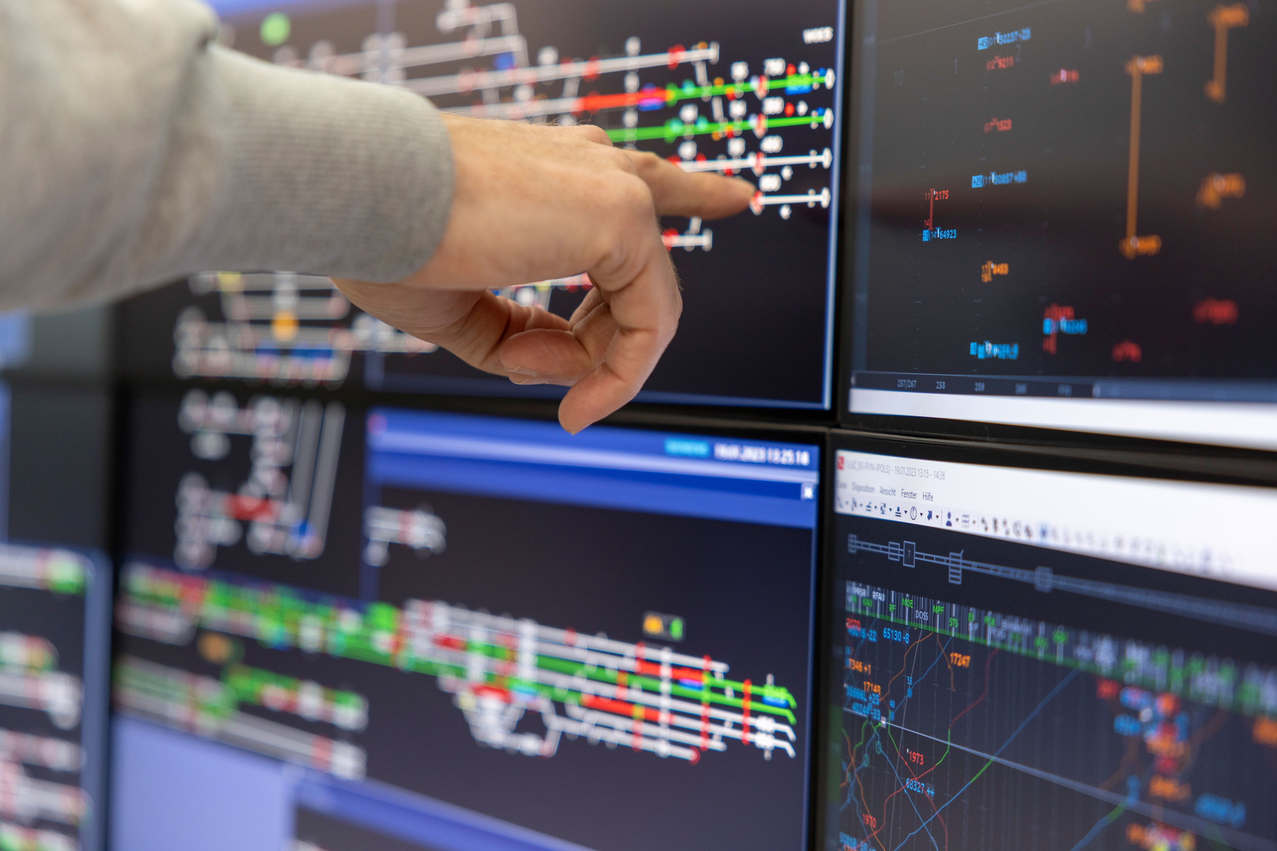 Eine Person zeigt mit dem Zeigefinger auf einen Monitor.