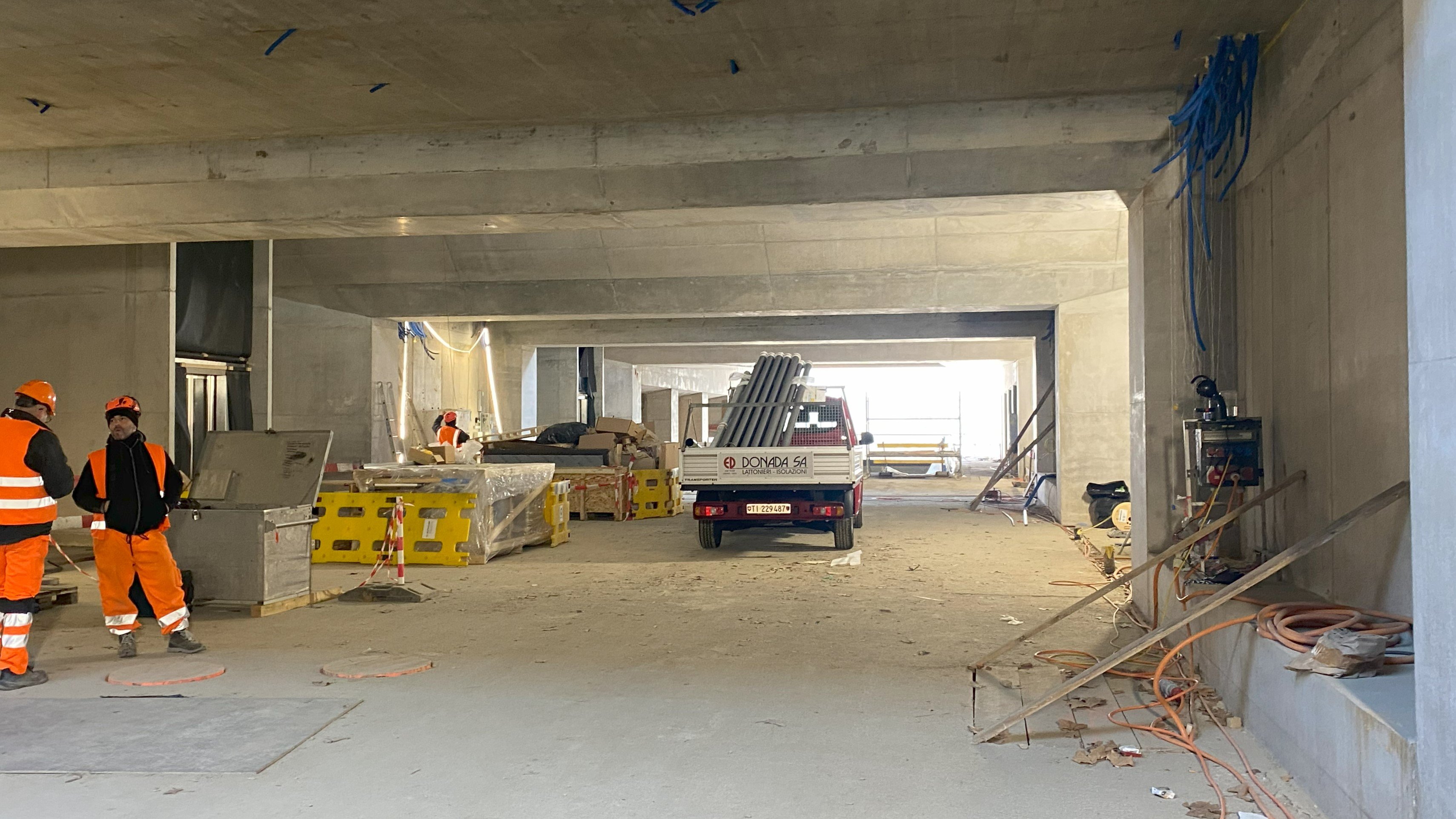 Il nuovo sottopasso ancora in costruzione, con le pareti in calcestruzzo, un veicolo di cantiere nel centro e sulla sinistra due operai al lavoro.