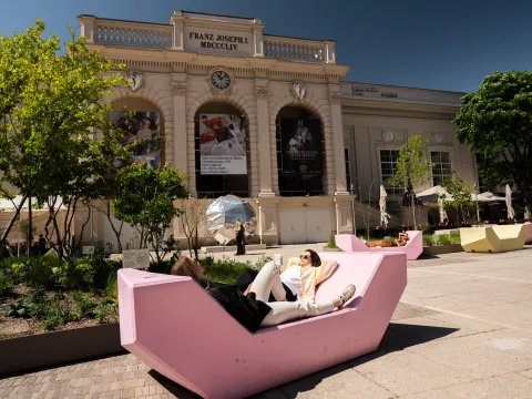 Due donne sono distese sulle panchine rosa nel cortile interno del MuseumsQuartier di Vienna in una giornata di sole.