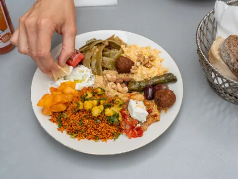Plateau de mezzés mixtes. Pain trempé à la main dans une sauce blanche.