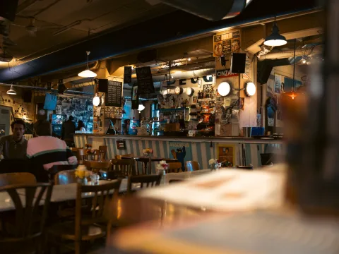 Comptoir de bar dans une salle de restaurant sombre. Les murs sont entièrement décorés d’affiches, de photos et de panneaux publicitaires.