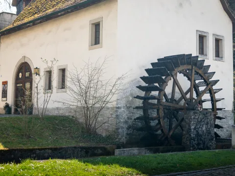 Ein historisches Haus mit einem seitlich angebrachten Mühlenrad.