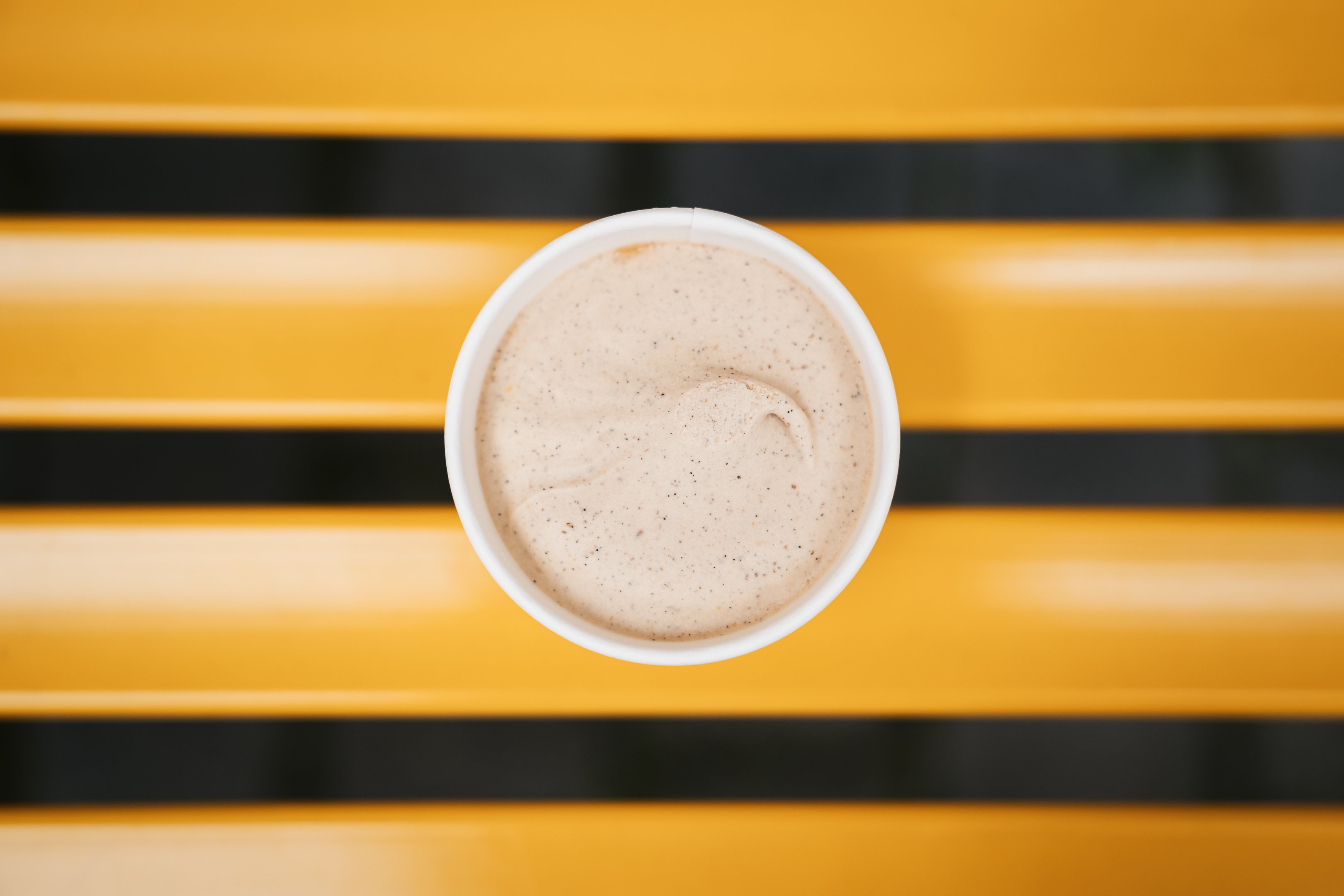 Una coppetta di gelato al gusto rooibos vanigliato, appoggiata su una panchina gialla.