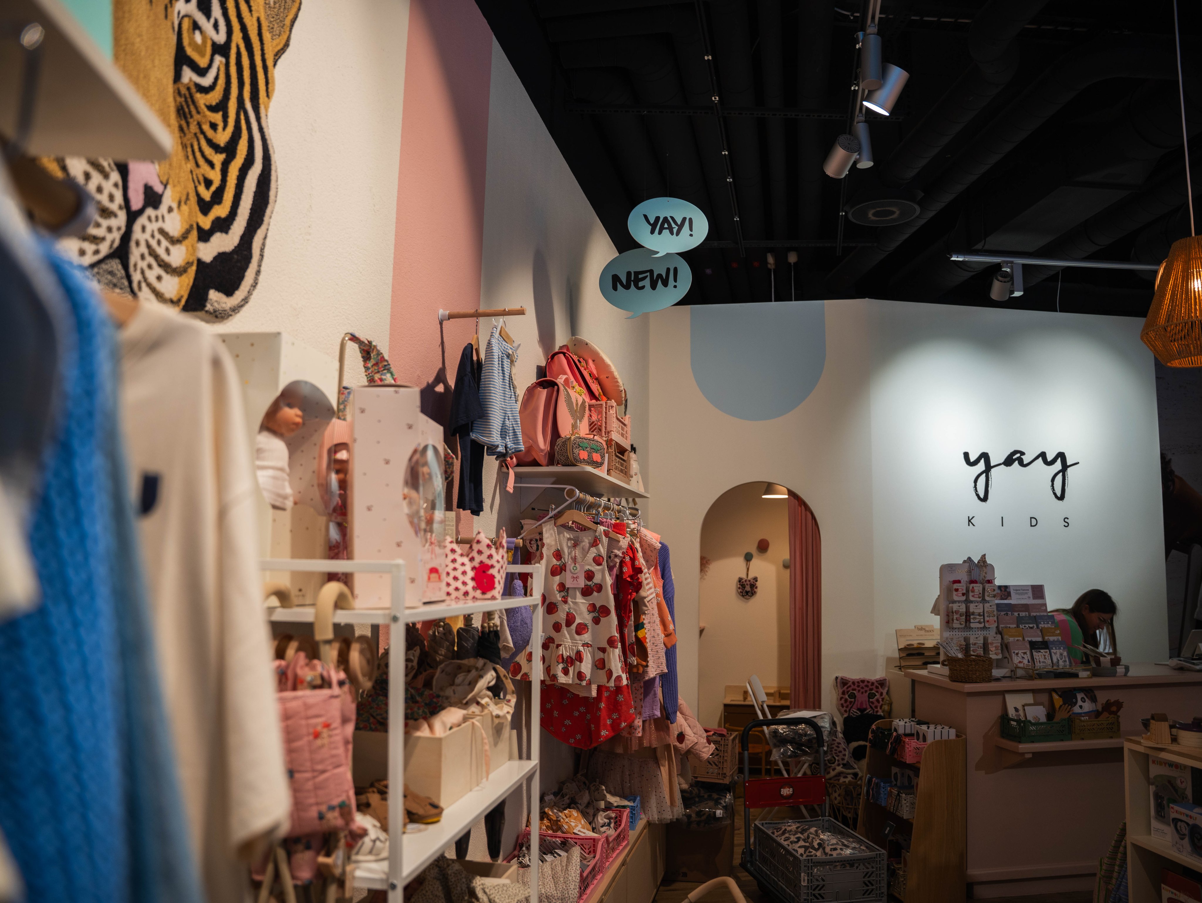 Bunte Kinderkleider an der Kleiderstange und Dekorationsartikel