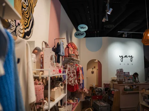 Bunte Kinderkleider an der Kleiderstange und Dekorationsartikel