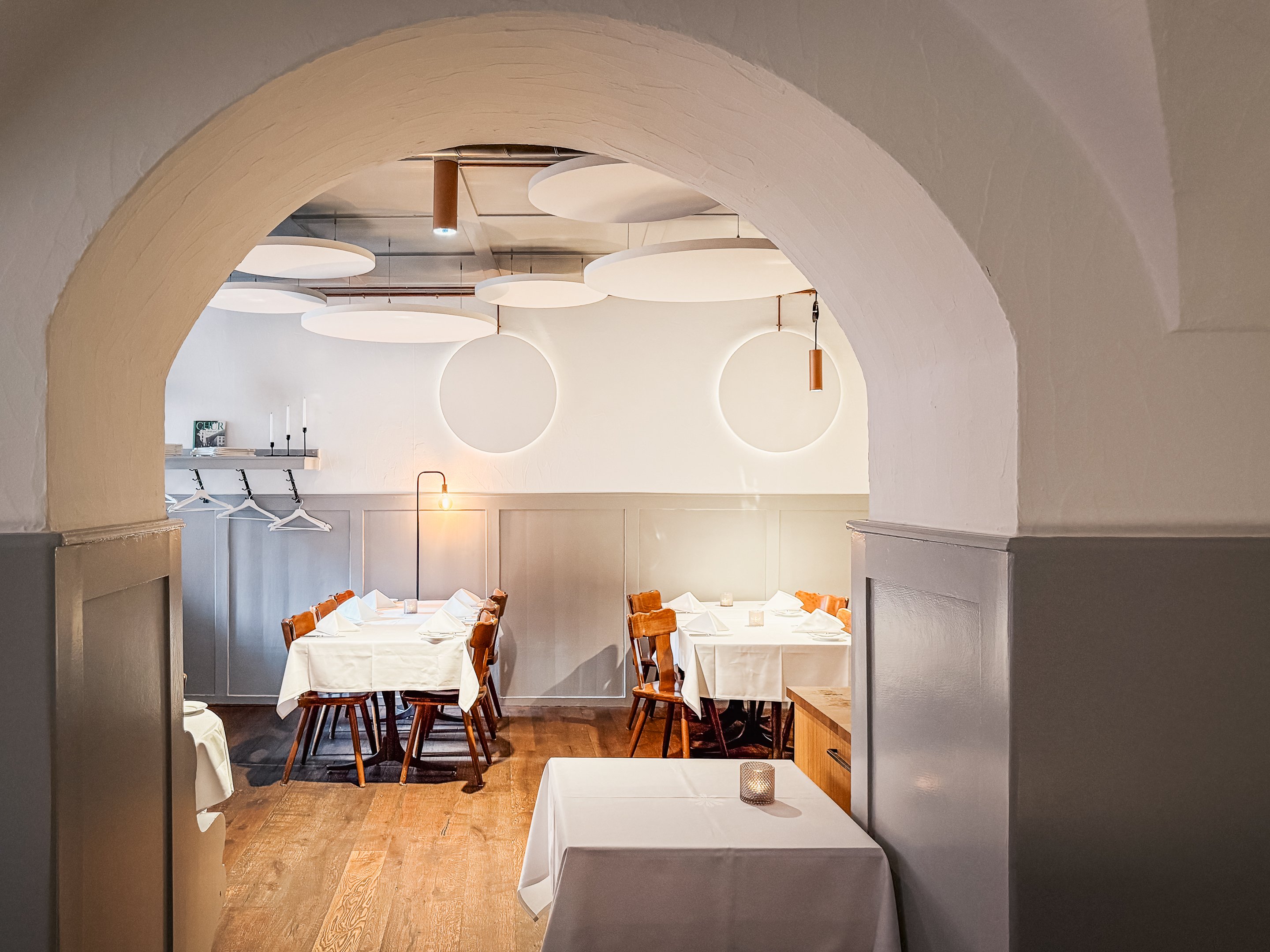 All’interno della brasserie Süsswinkel si vedono due tavoli apparecchiati e luci moderne alle pareti.