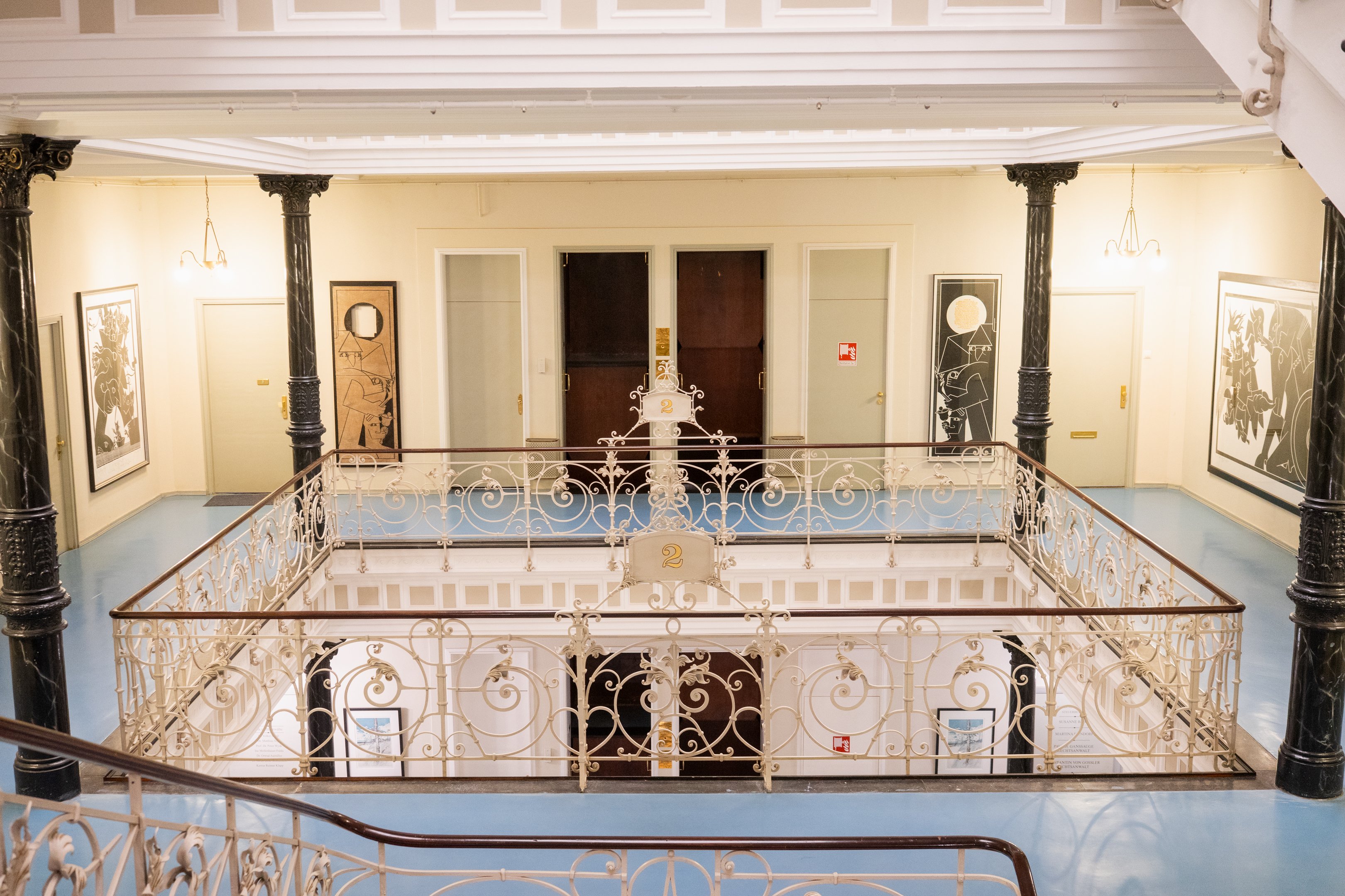 Ein Blick in den Lichthof mit gusseisernen Geländer und dem Paternosteraufzug im Hintergrund.