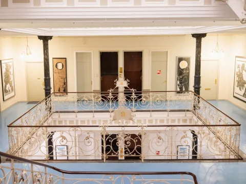 Ein Blick in den Lichthof mit gusseisernen Geländer und dem Paternosteraufzug im Hintergrund.