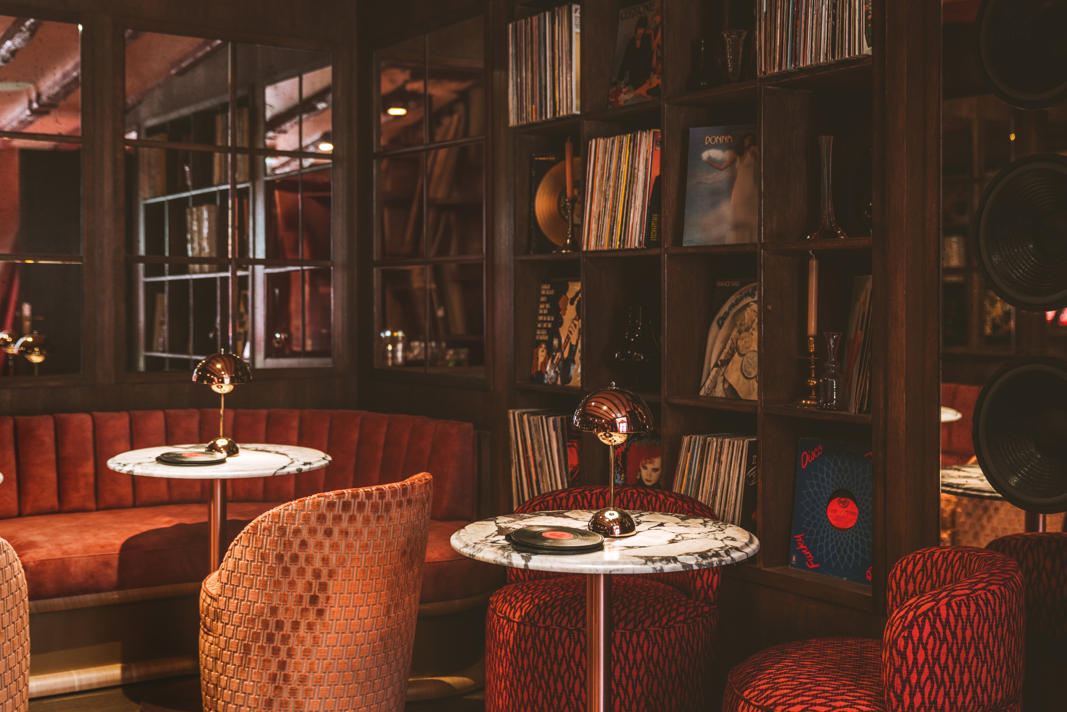 Aménagement intérieur du Grouvie: banquettes et fauteuils recouverts de velours et baignés dans une lumière rougeâtre.