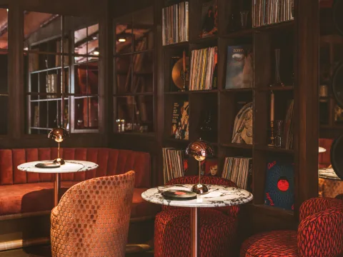 Aménagement intérieur du Grouvie: banquettes et fauteuils recouverts de velours et baignés dans une lumière rougeâtre.