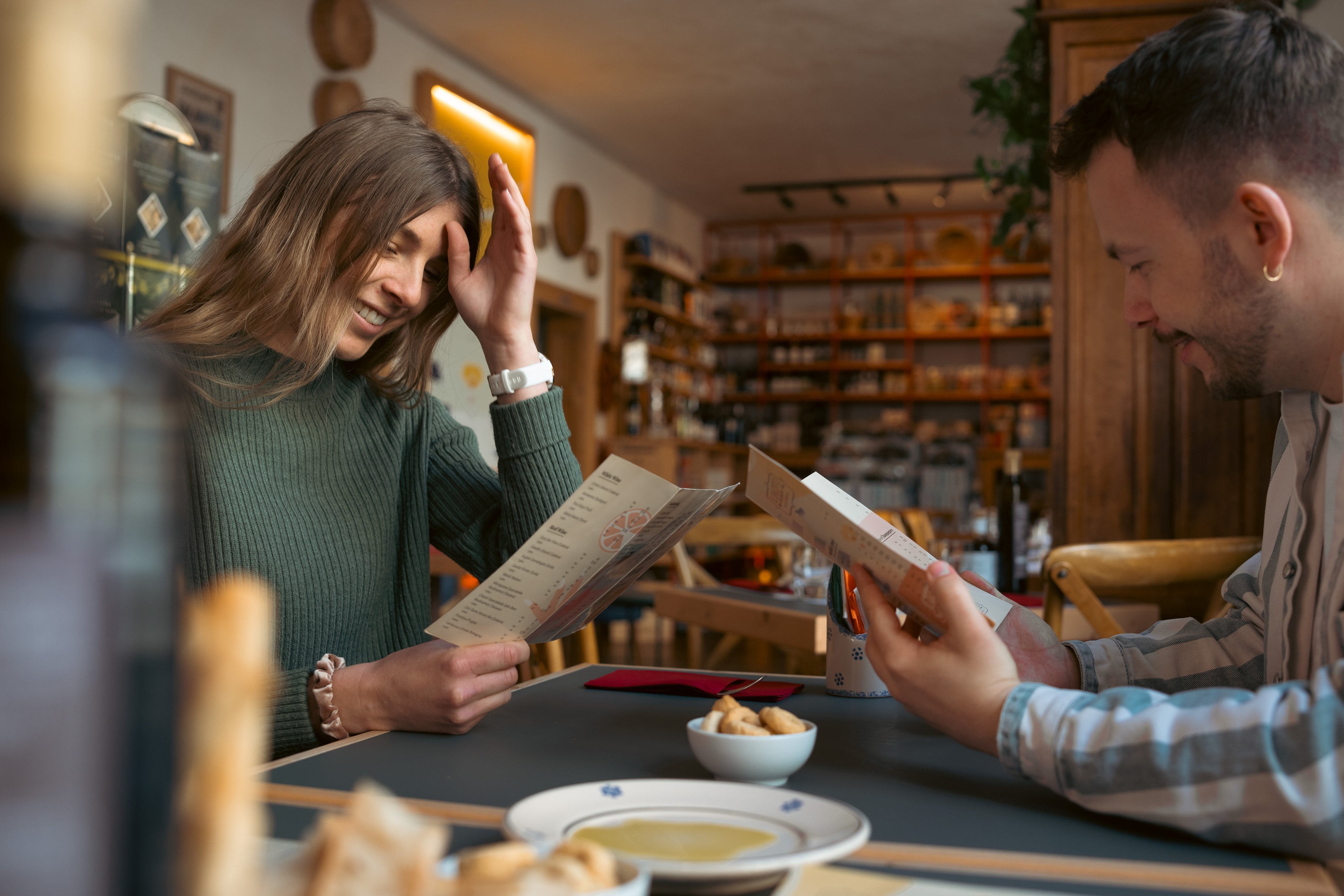 Deux personnes assises à la table d’un restaurant lisent la carte. 