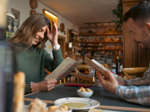 Deux personnes assises à la table d’un restaurant lisent la carte.