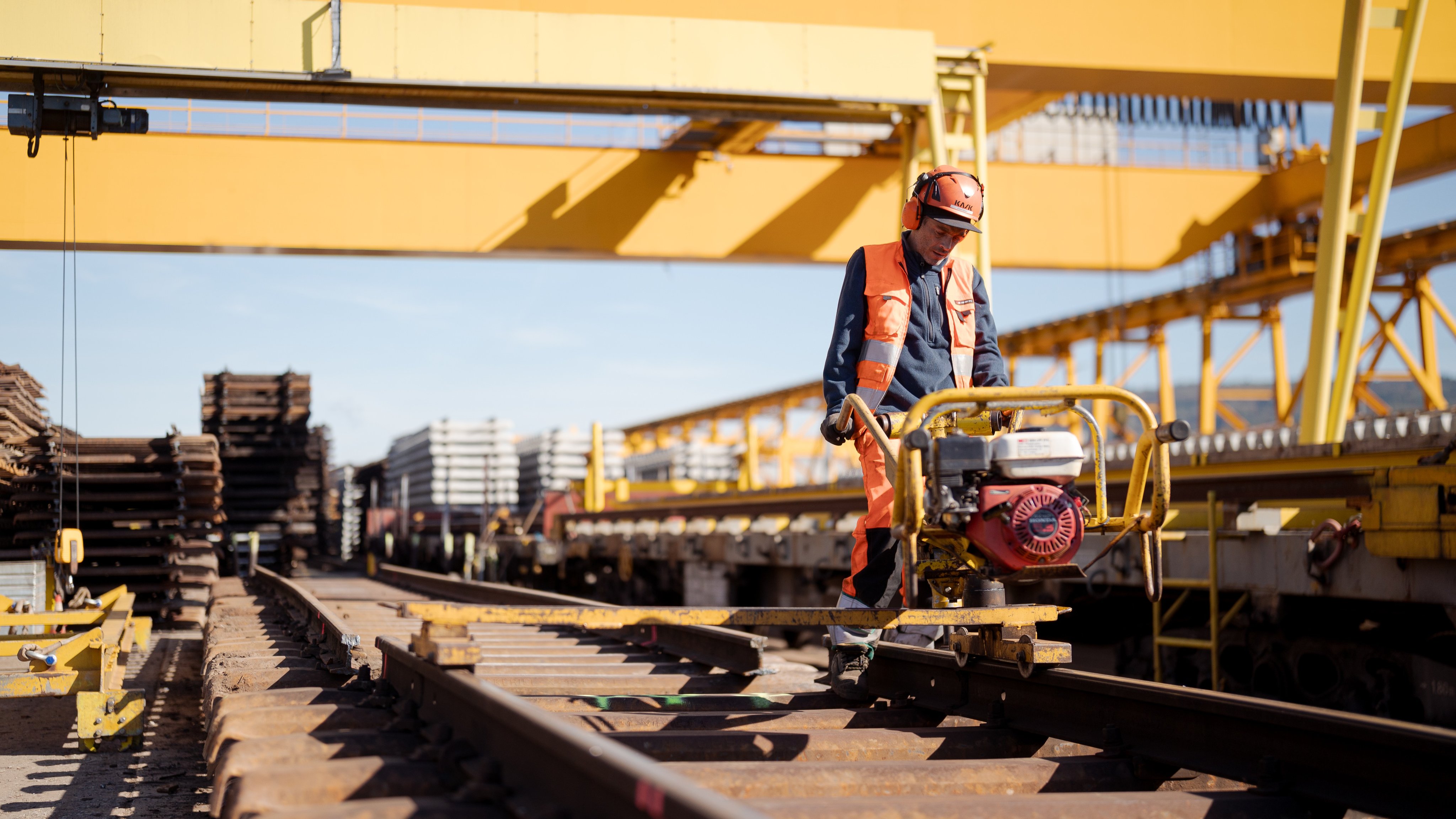Un collaborateur traite un rail à l’aide d’une machine.