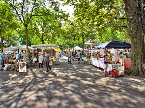 Menschen schlendern an Verkaufsständen vorbei am Flohmarkt Bürkliplatz.