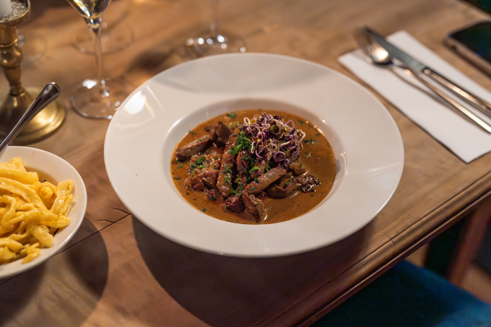 Rindfleischgericht in einer braunen Sauce angerichtet in einem weissen Teller mit Spätzle. 
