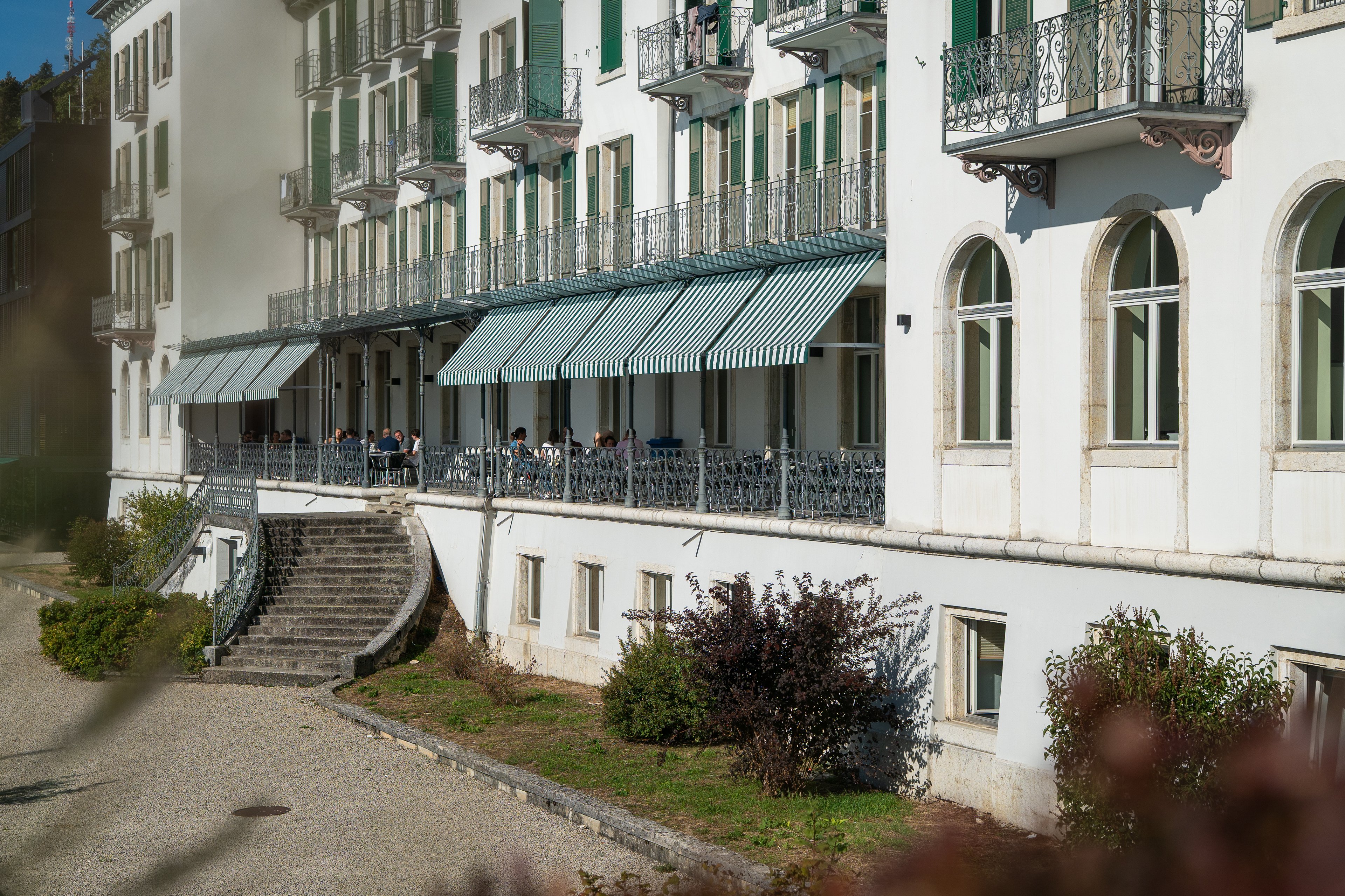 Facciata storica del Grand Hotel di Macolin, con terrazza coperta e tende da sole bianche e verdi.