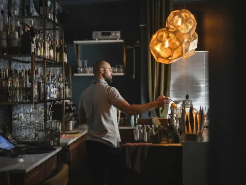 Der Bartender lässt hinter der Bar Saft durch ein Sieb ins Cocktailglas fliessen.