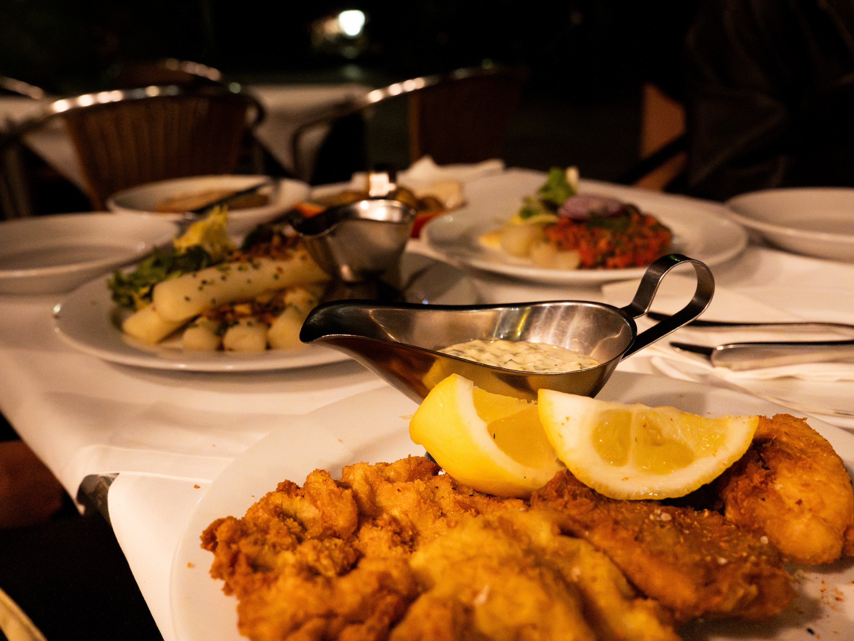 Cotoletta viennese con spicchi di limone e salsa su un tavolo apparecchiato nel Restaurant Salzamt di Vienna.