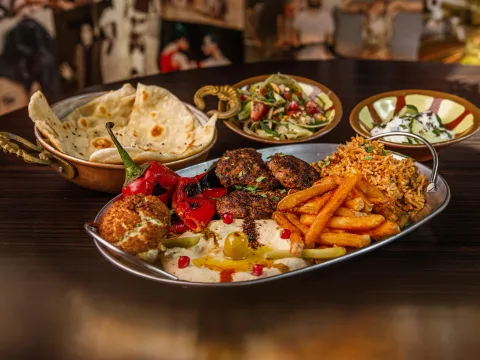 Un piatto köfte con köfte, hummus, patate a spicchi, riso, insalata, pane arabo e salsa allo yogurt.