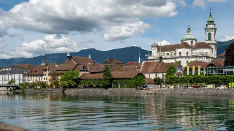 Ansicht einer Stadt mit einer grossen Kirche, im Vordergrund ein Fluss.
