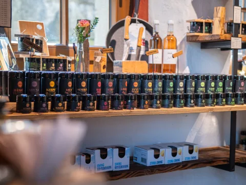 Gewürze stehen dicht aneinandergereiht auf einem Regal mit dekorativen Elementen.