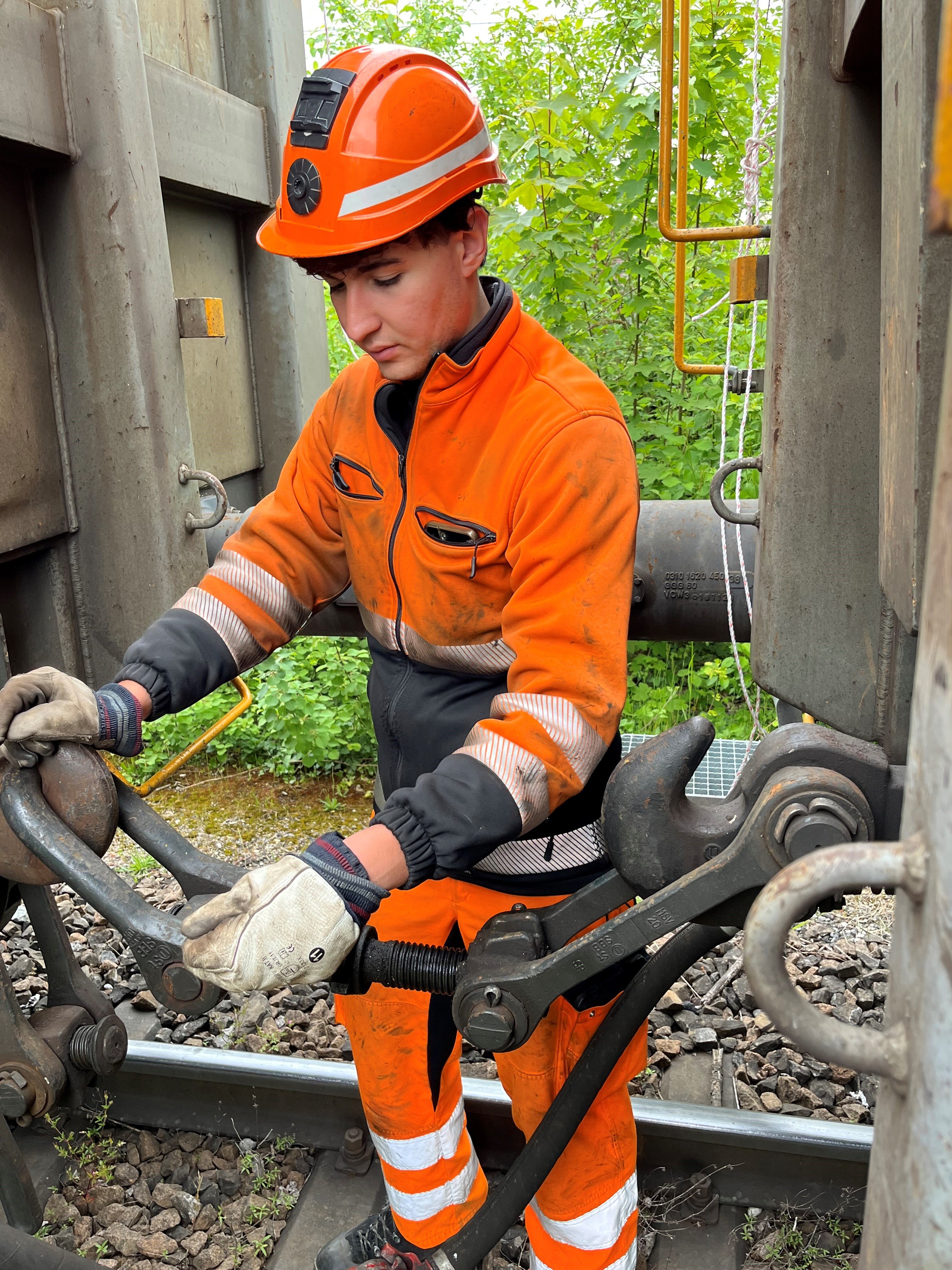 Isaia Colucci steht zwischen zwei Güterwagen und kuppelt die beiden Wagen aneinander.