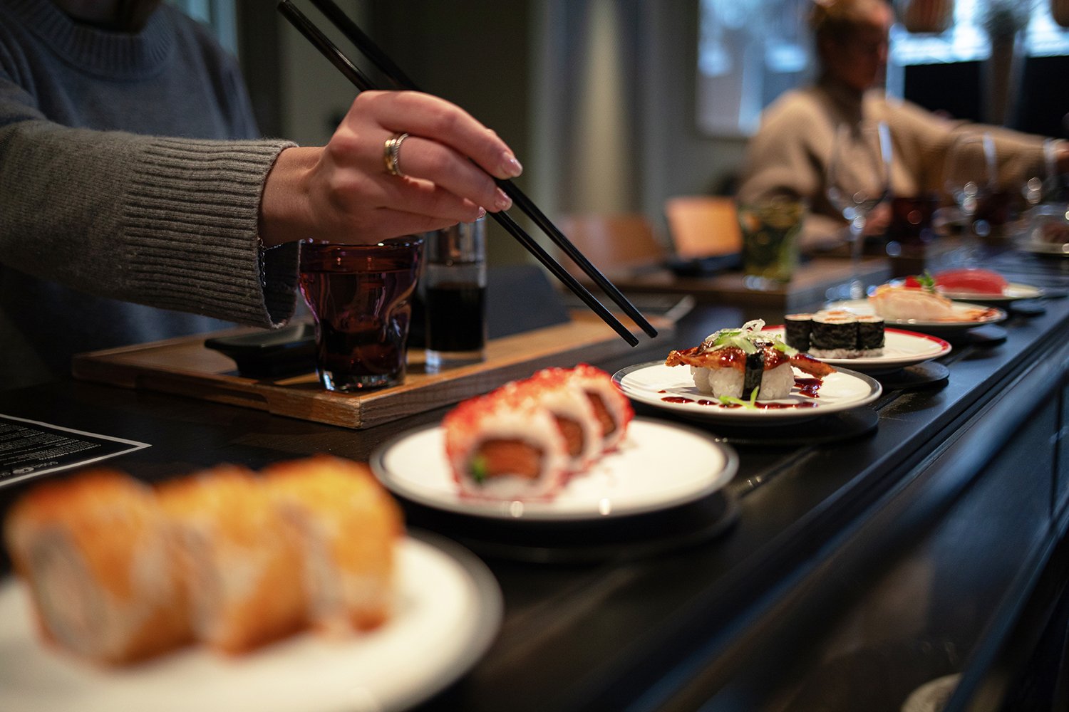Piatto pieno di sushi su un nastro trasportatore.