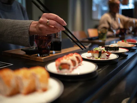 Piatto pieno di sushi su un nastro trasportatore.