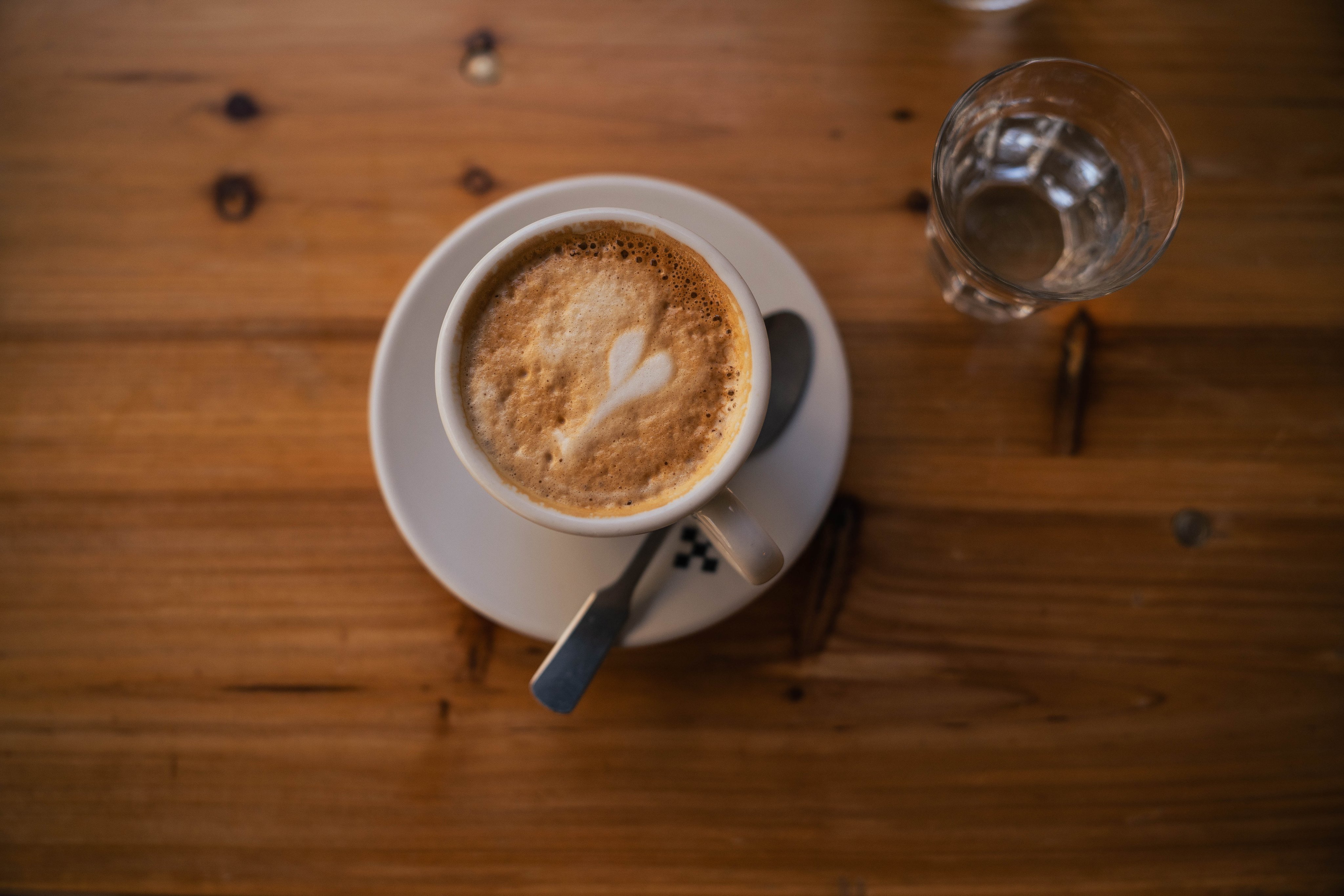 Un tavolo di legno con una tazza di caffè macchiato.  